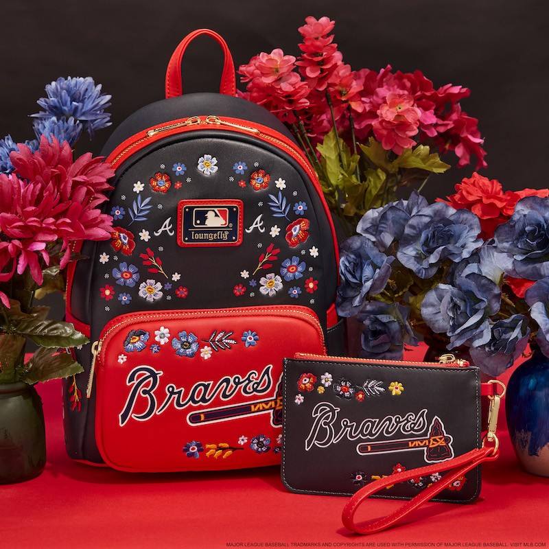 Navy blue and red Loungefly Atlanta Braves mini backpack and wristlet clutch against a red and navy background with dark blue and red flowers around them